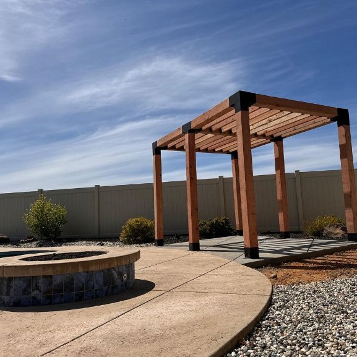 Curved concrete patio in Redding, CA with pergola and circular fire feature