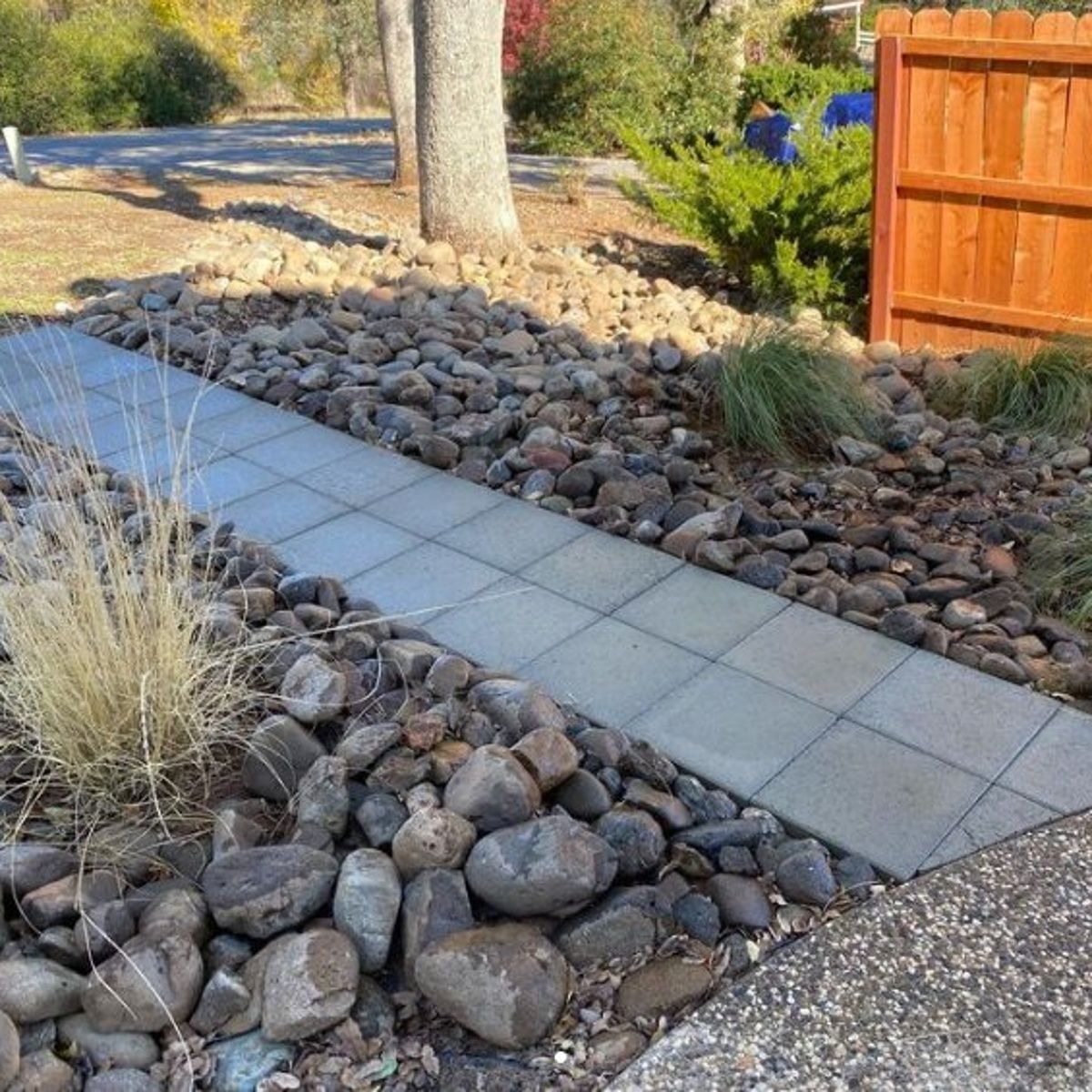 Concrete walkway in Redding, CA bordered by river rock and low-maintenance landscaping