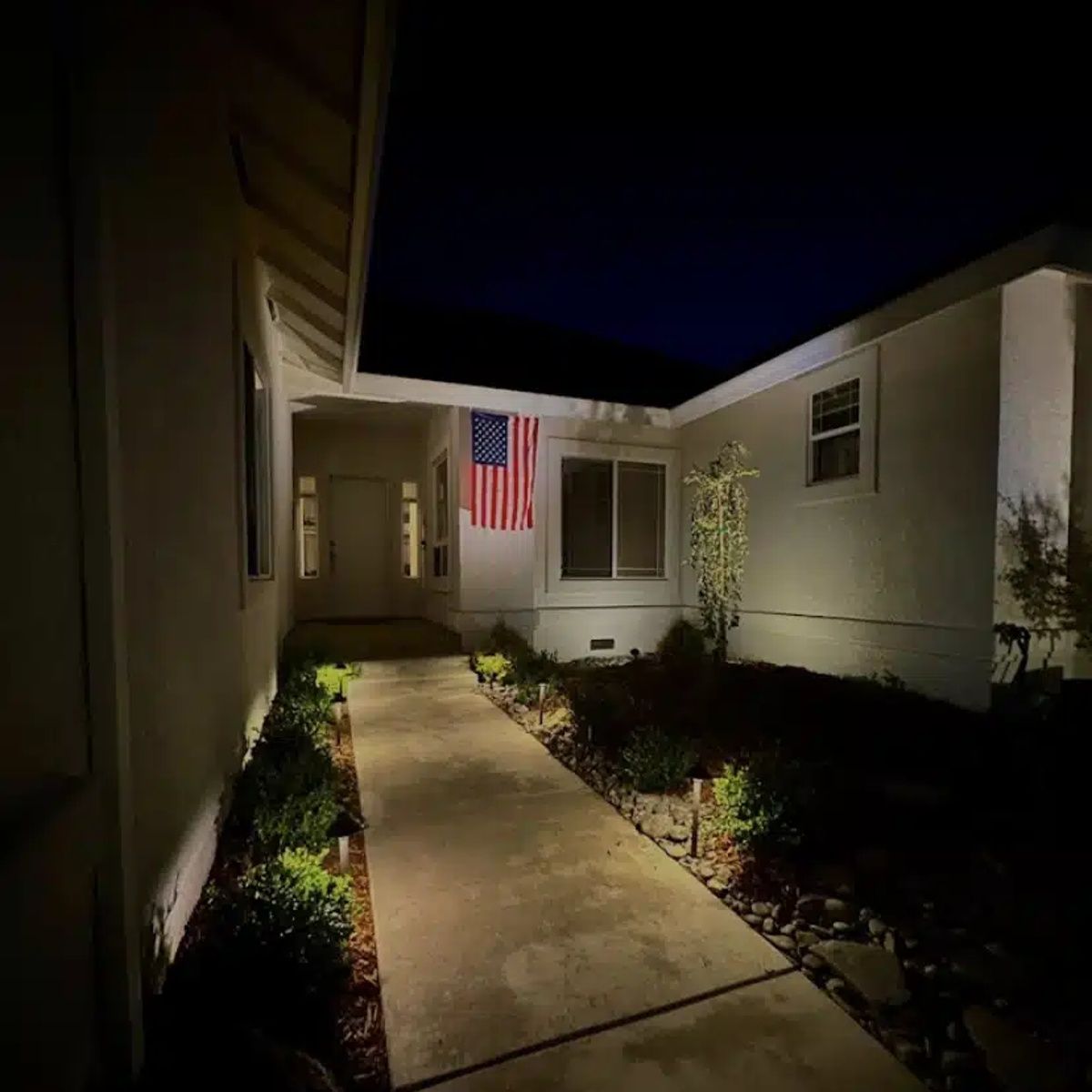 Concrete entry walkway in Redding, CA with landscape lighting at night