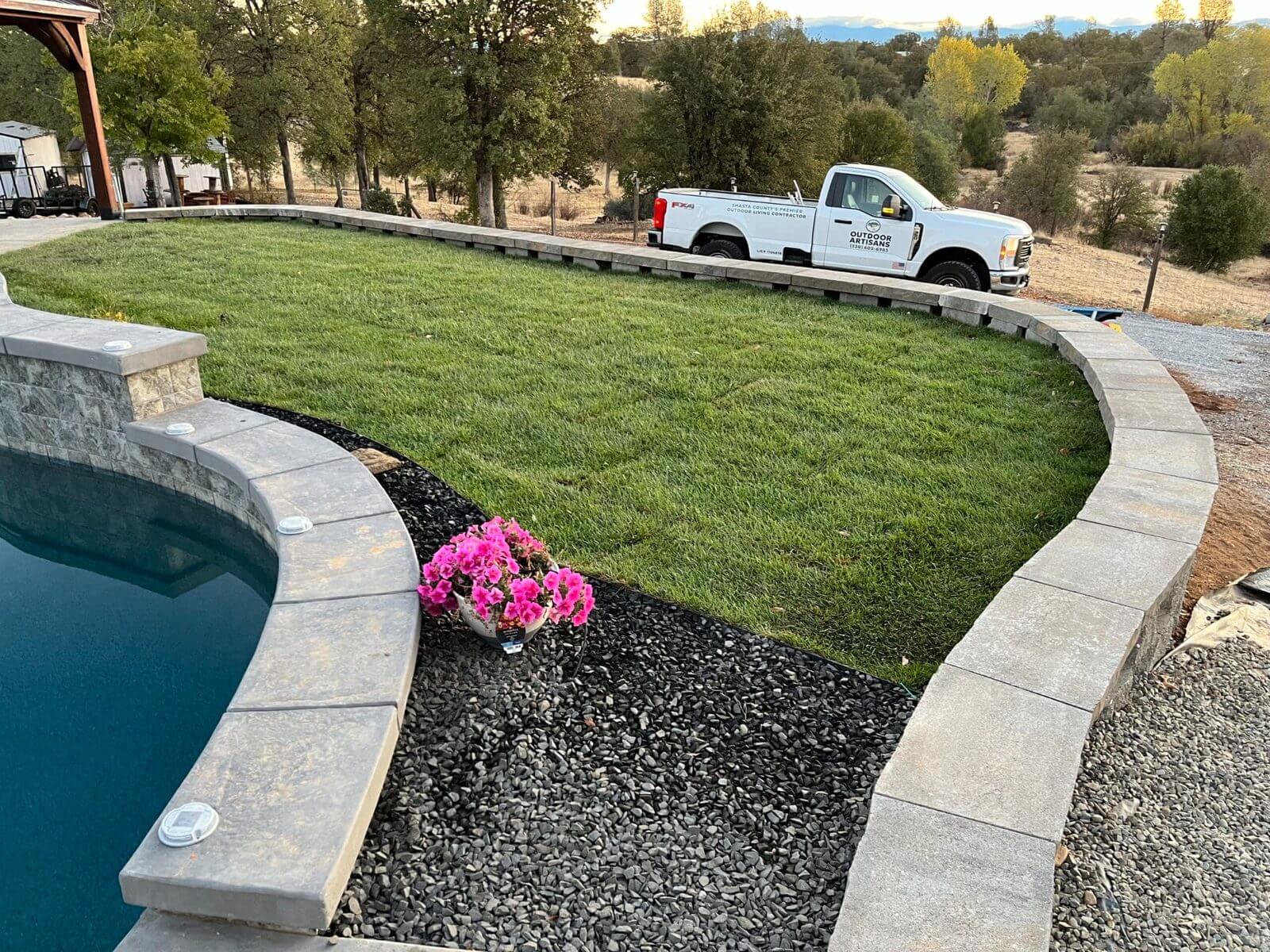 Curved sod lawn installation in Redding, CA beside pool and retaining wall