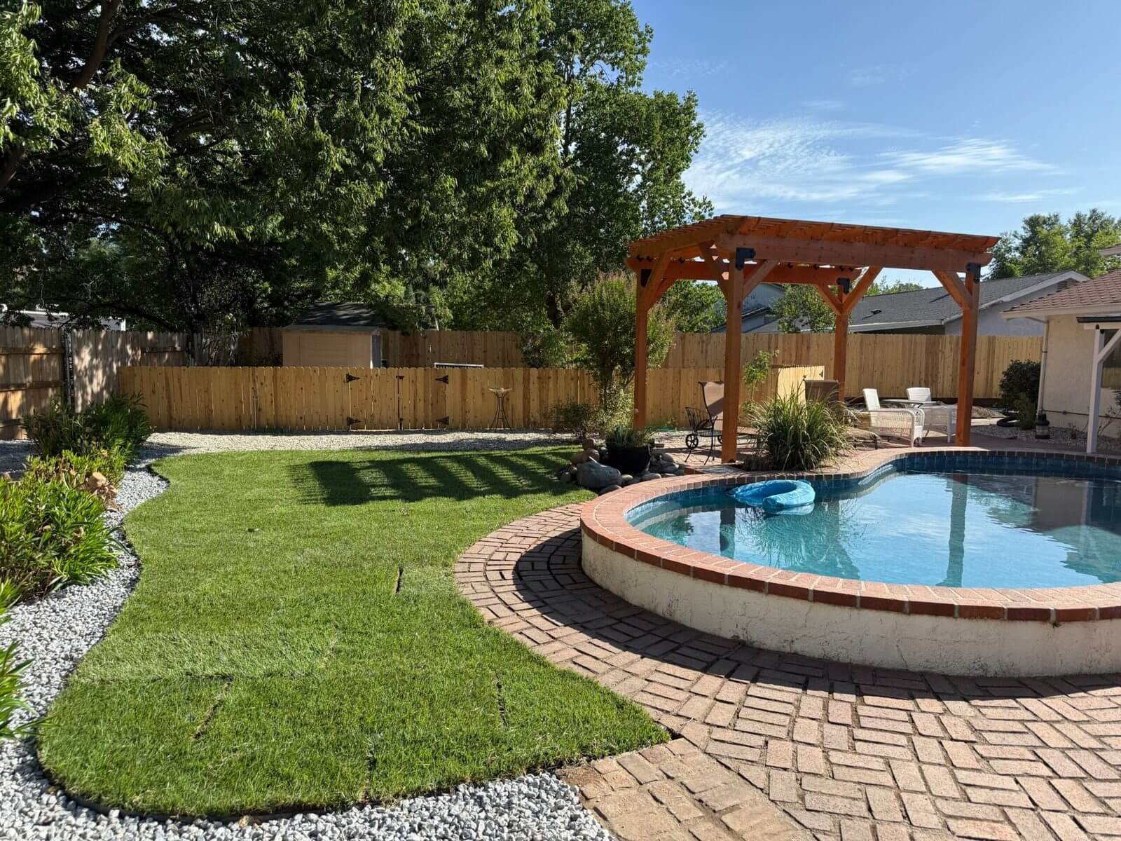 Backyard sod installation in Redding, CA with pergola, pool, and finished lawn area