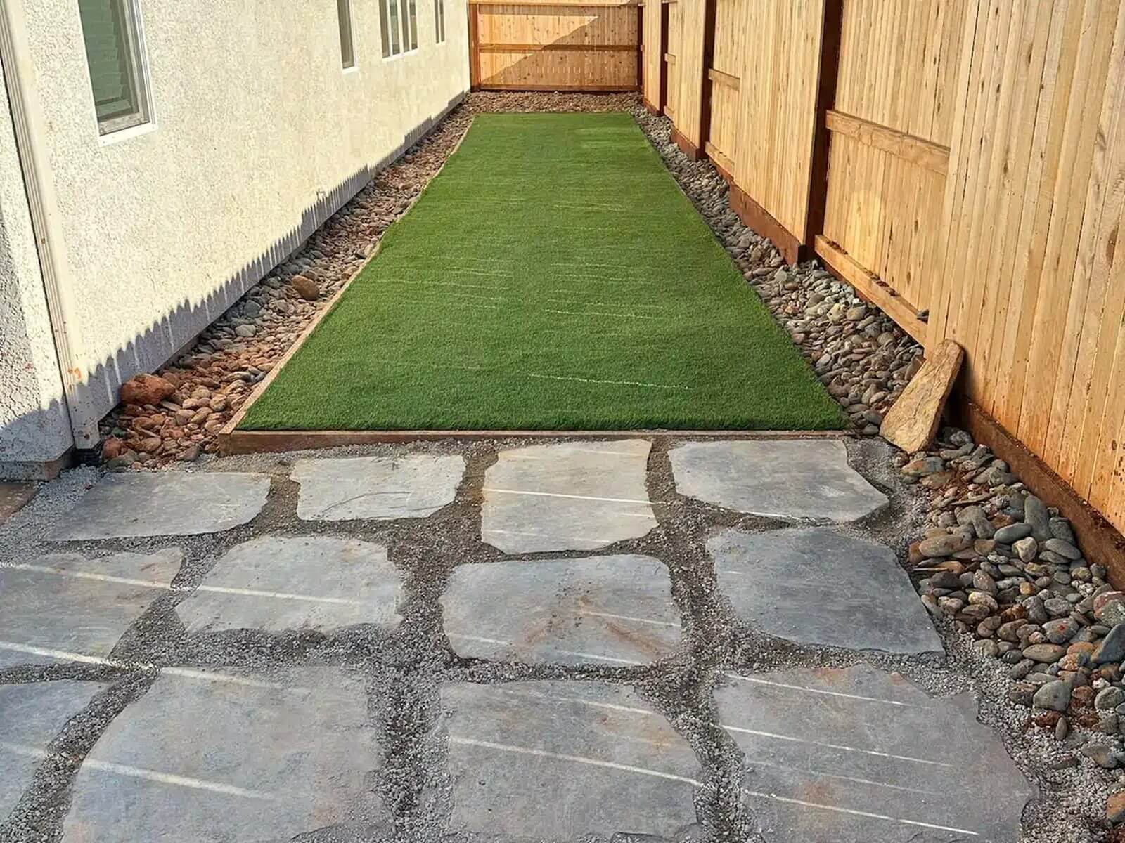 Side yard lawn installation in Redding, CA with flagstone walkway and rock borders