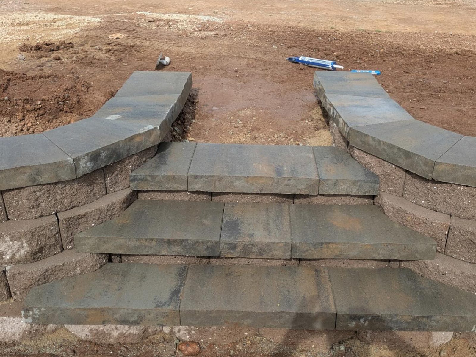 Curved retaining wall installation in Redding, CA with block steps and concrete wall caps