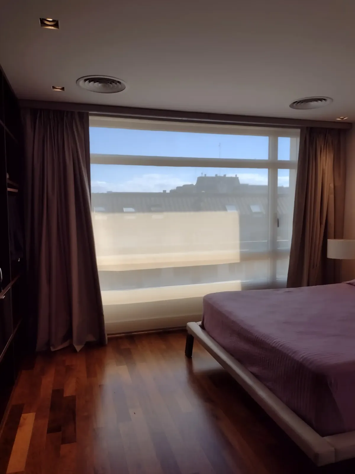 Habitación cómoda moderna con un ventanal tapado con cortinas blackout