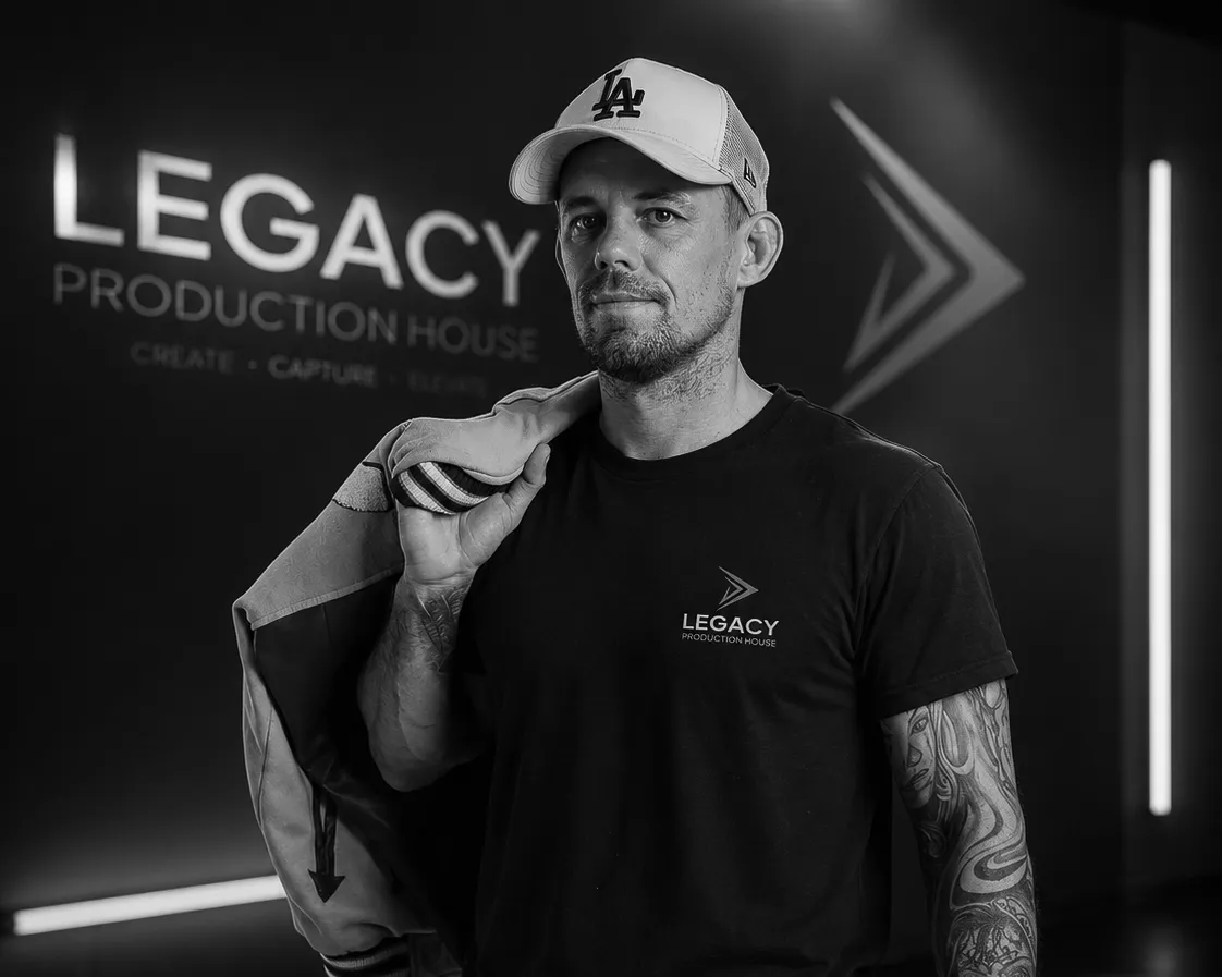 High-contrast cinematic monochrome portrait of Legacy Production House lead director on set with professional cinema monitor and camera rig