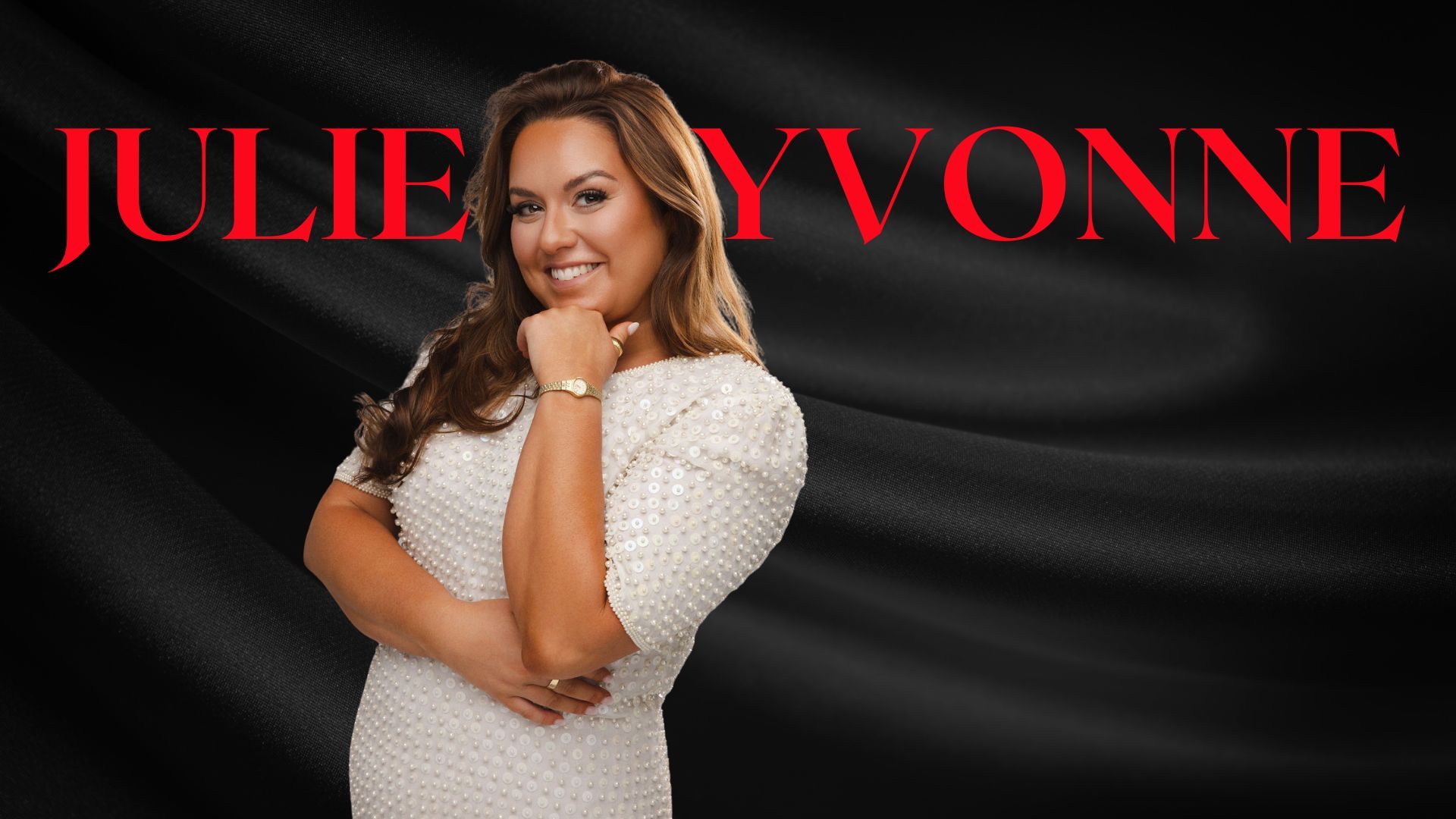 Woman in a black dress with her hands on her hips, smiling, set against a dark background with large red typography