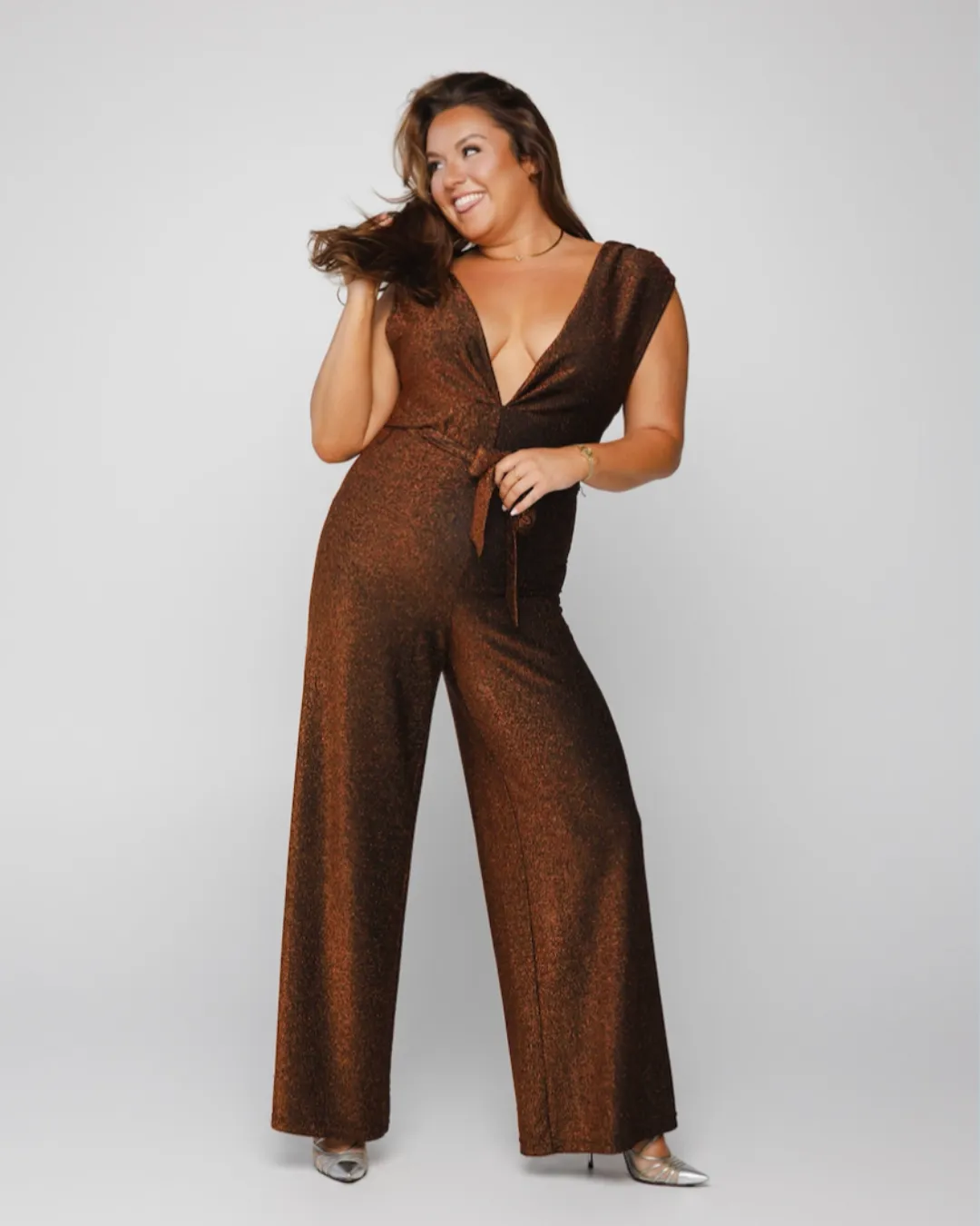 Woman in a brown patterned suit sitting on the floor against a white background