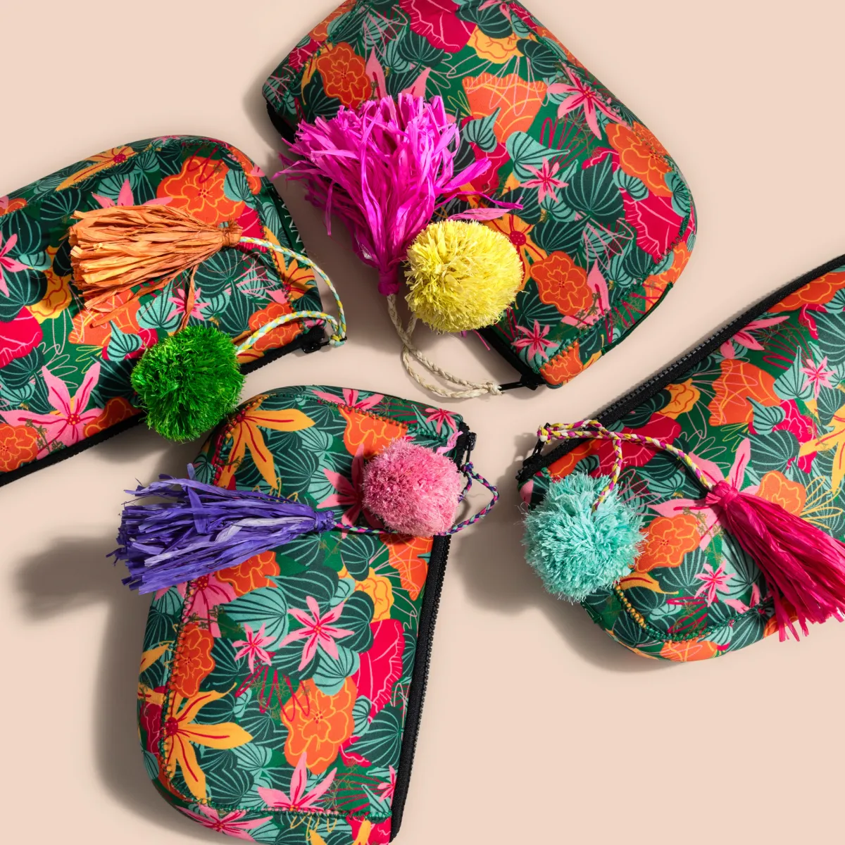 Four colorful Anna's travel bags each adorned with distinct tassels, displayed against a peachy background., 