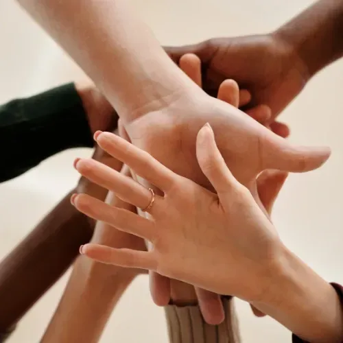 Six hands of different colors stacked one on top of the other, symbolizing diversity and connection for the 'Let's Connect' page.