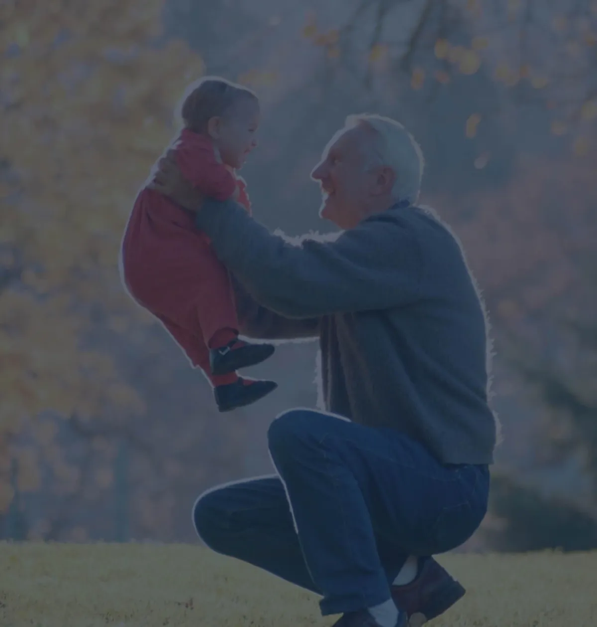A grandfather lifting his smiling granddaughter in a park