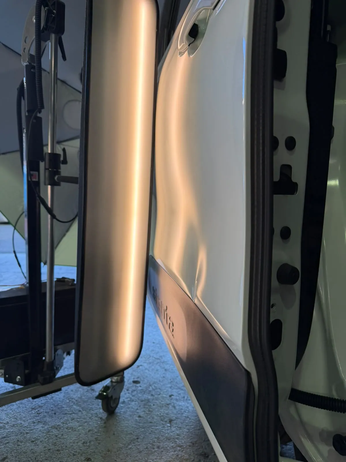 Dent in door of white vehicle