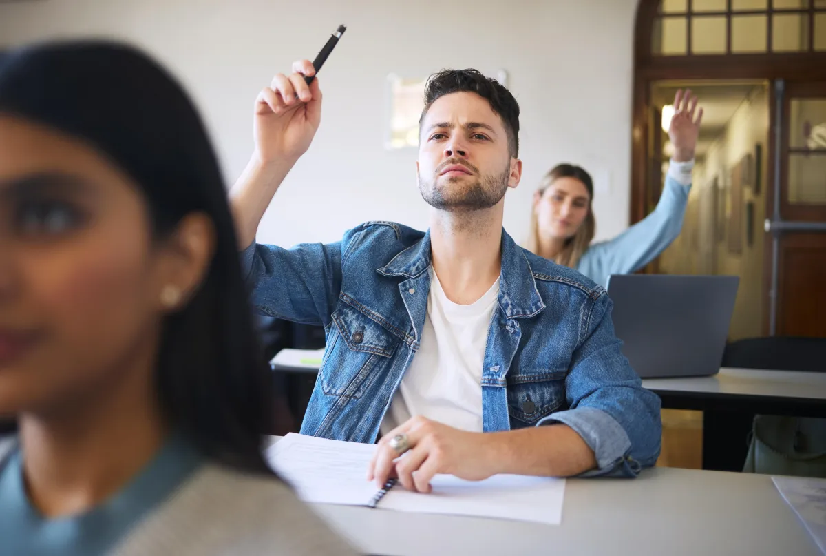 young white male raising their hand in a class