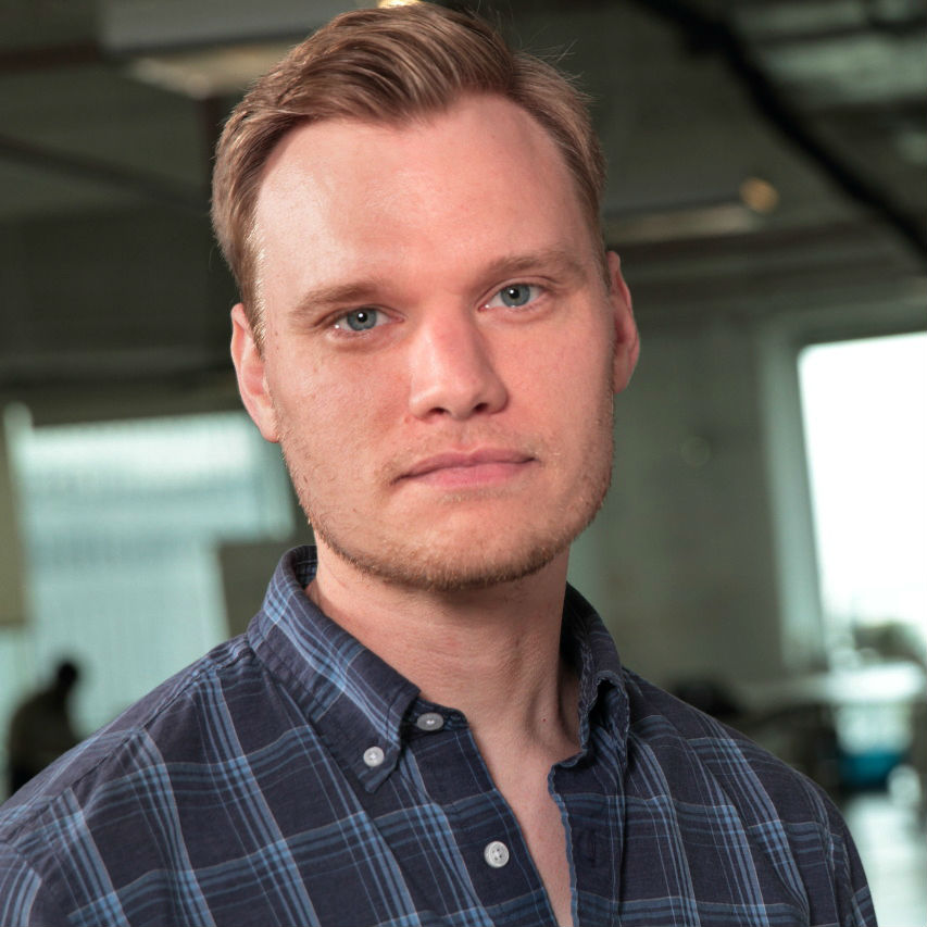 Headshot of Eric Sundal, founder, wearing a navy blazer and white shirt against a light-gray studio background.