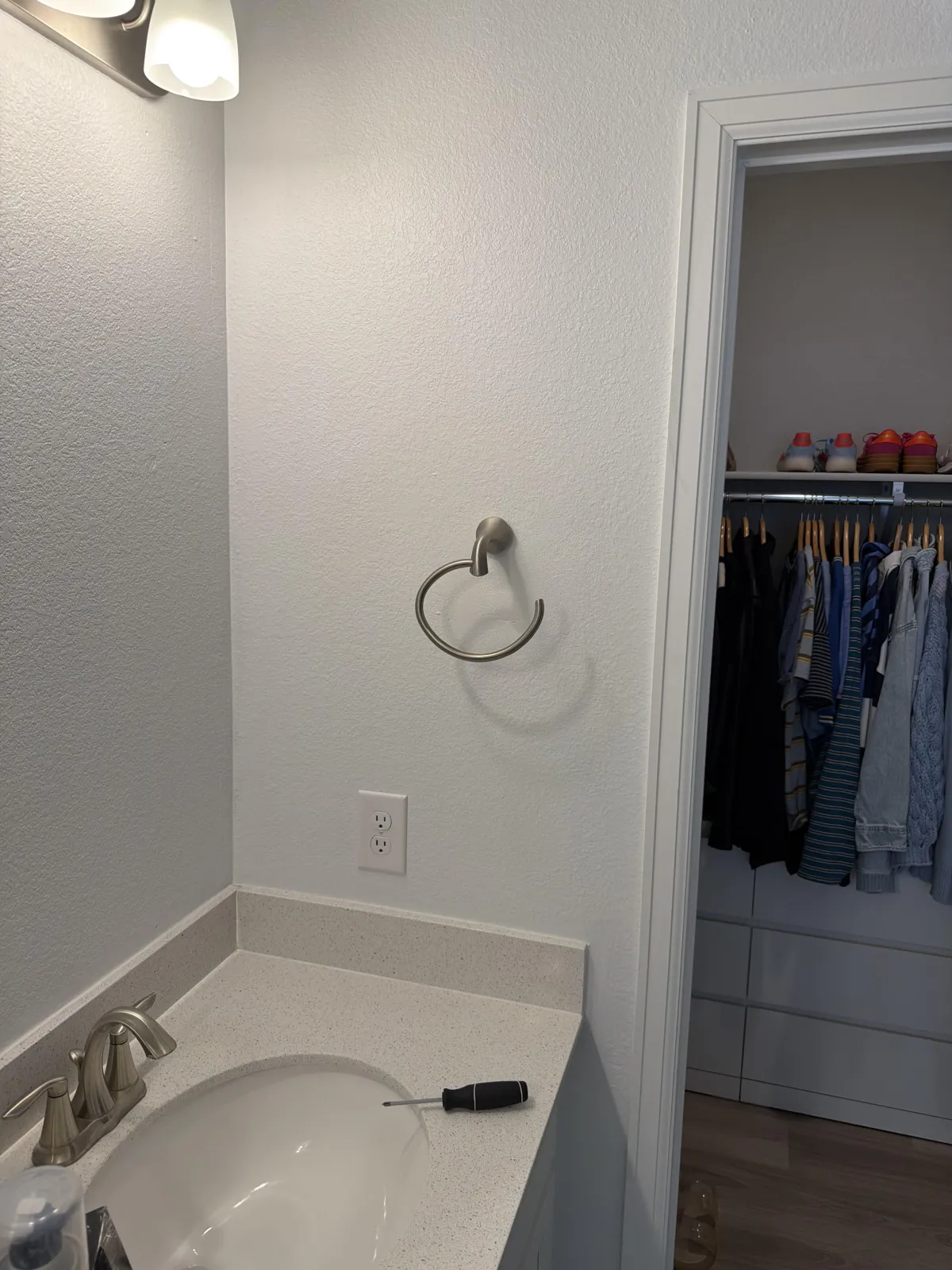 Bright, modern bathroom featuring a white freestanding bathtub next to a window, a dark wood vanity with a white top, and two mirrors.