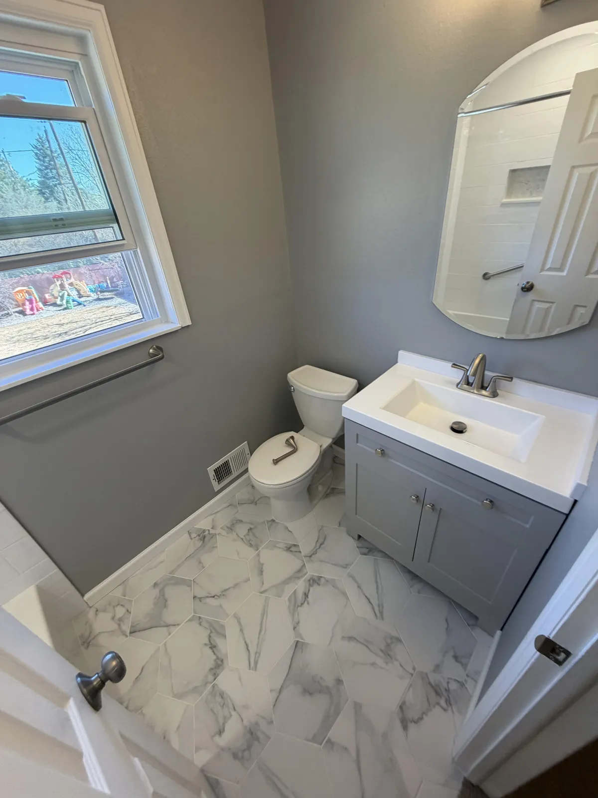 Wide view of a large dark wood bathroom vanity with dual sinks, mirrors, and sconce lighting.