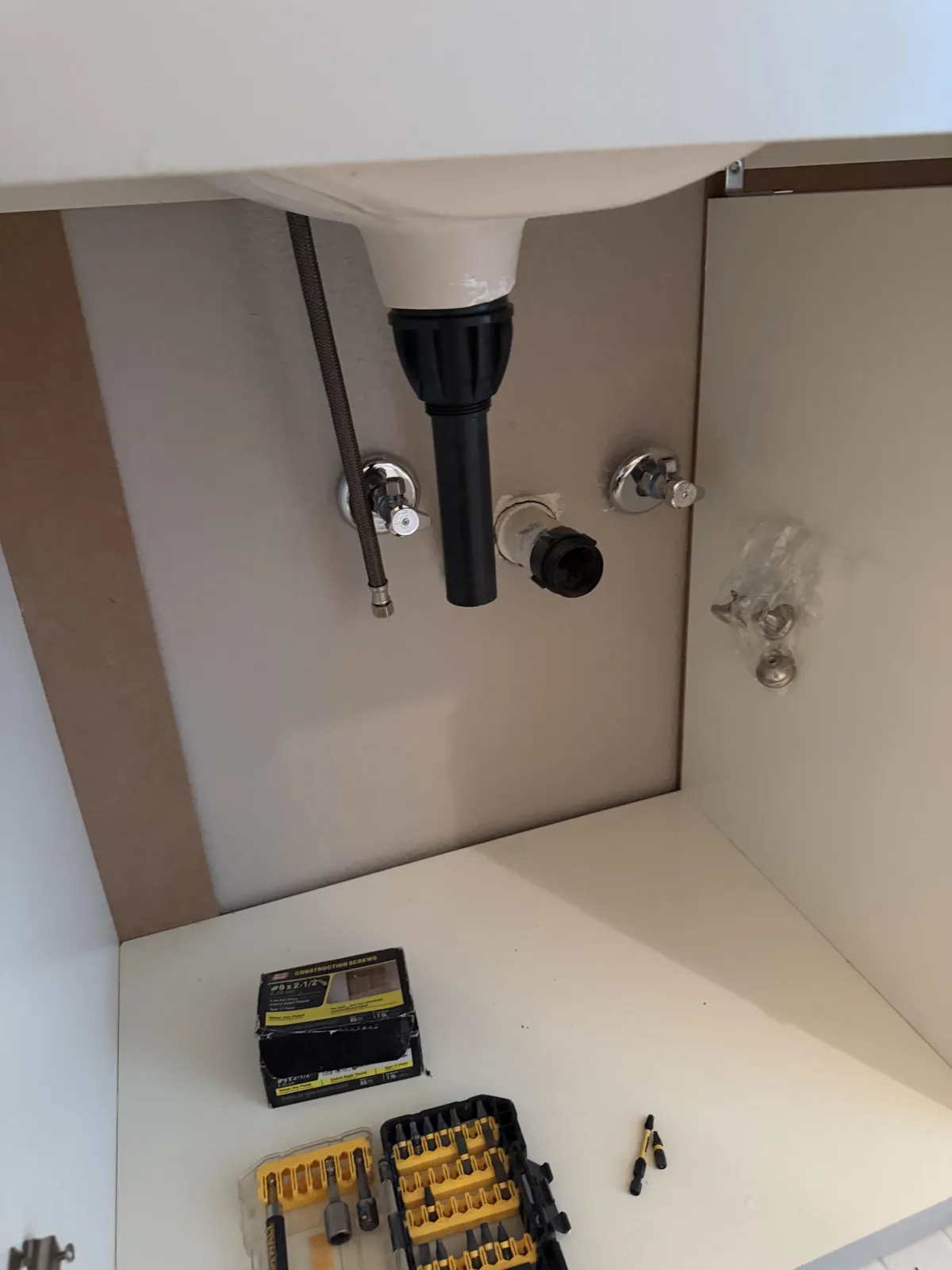 Close up of a matte black modern bathroom sink faucet with water running into a white basin.
