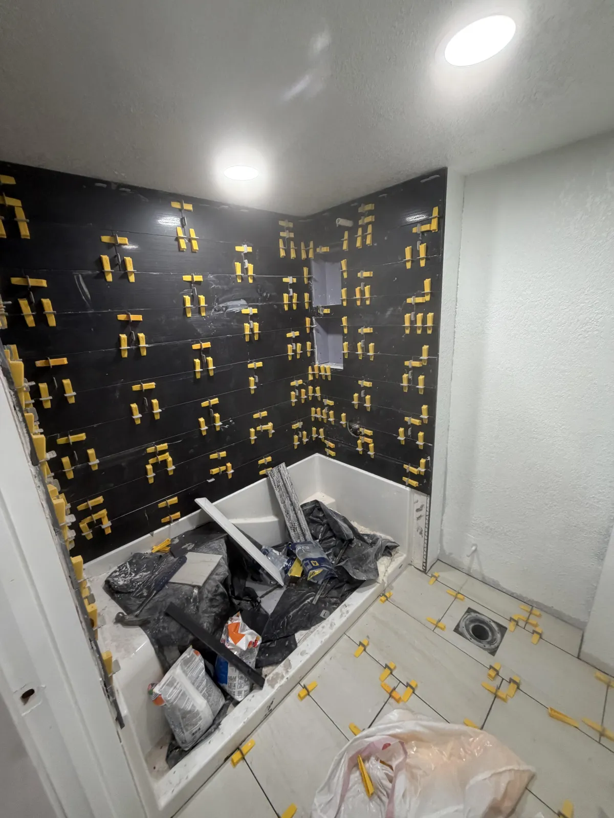Modern bathroom interior showing a glass shower enclosure with black fixtures and a white vanity sink.