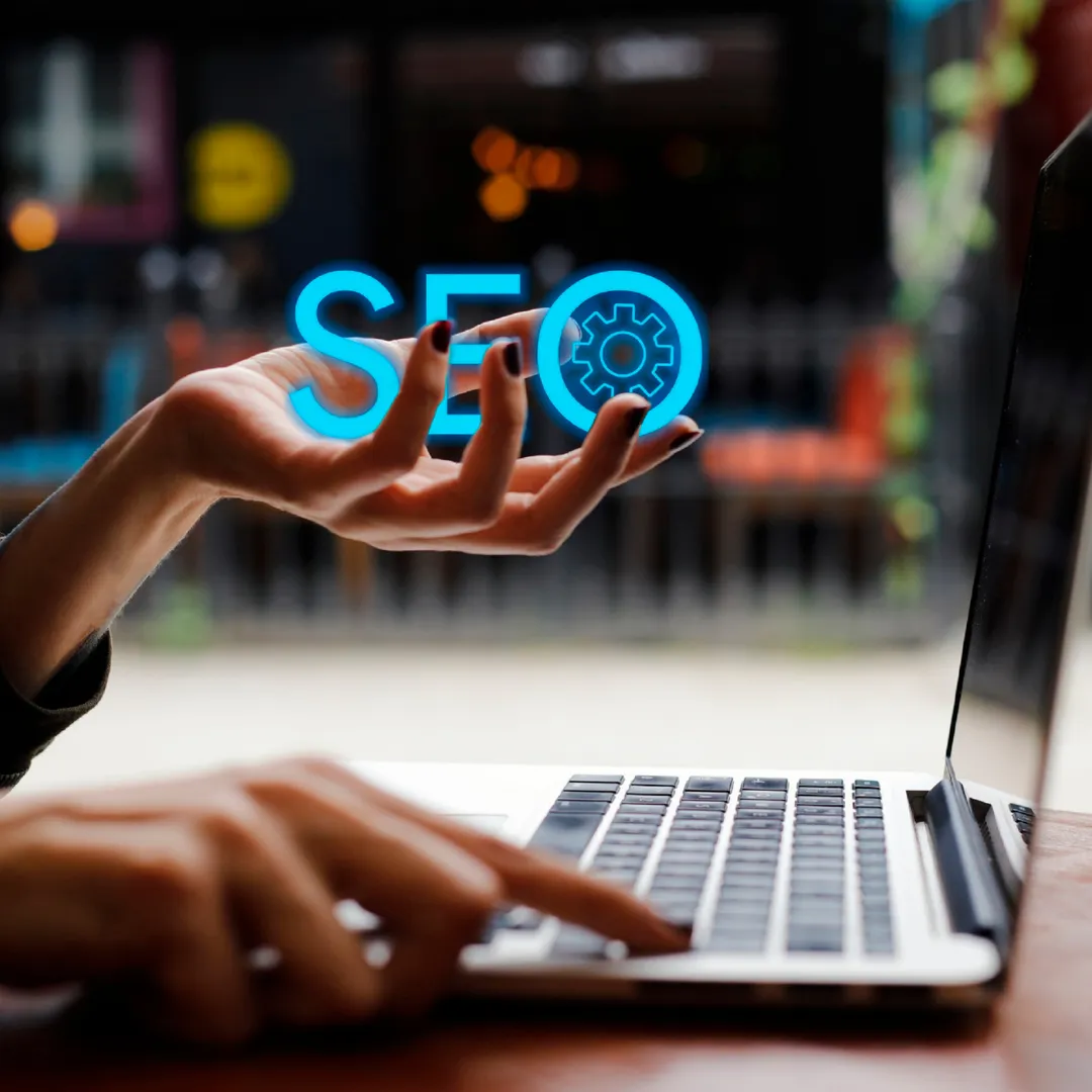 Someone using a laptop holding the word SEO in their hand 