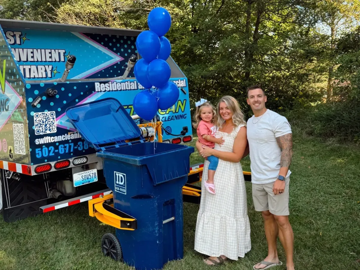 A family of three (parents and young daughter) smiling in front of a SwiftCan Cleaning truck, a blue trash can, and balloons.