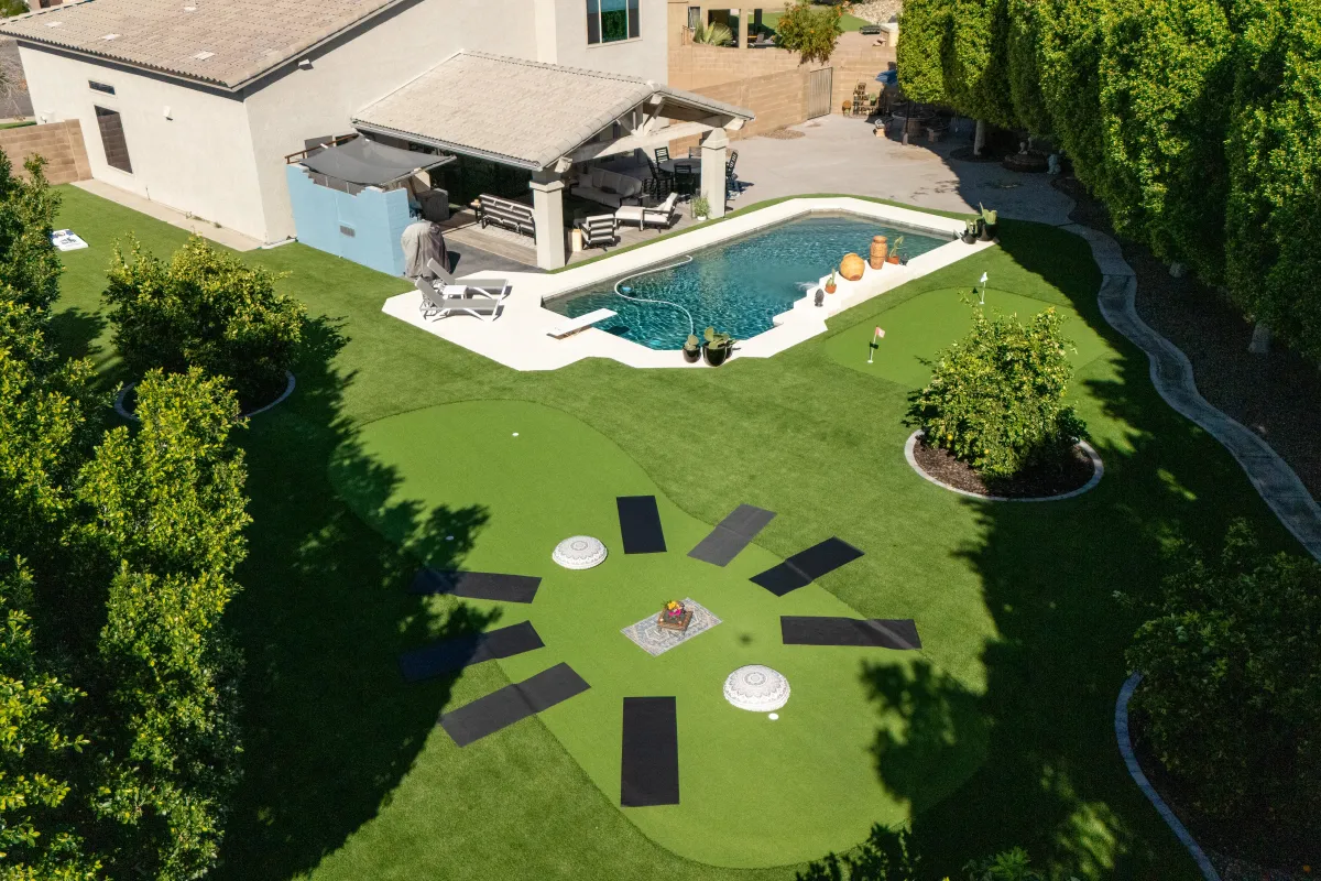 A modern home exterior with a sparkling heated pool, surrounded by palm trees and comfortable lounge chairs, under a clear blue sky, exuding relaxation and luxury in a private setting.