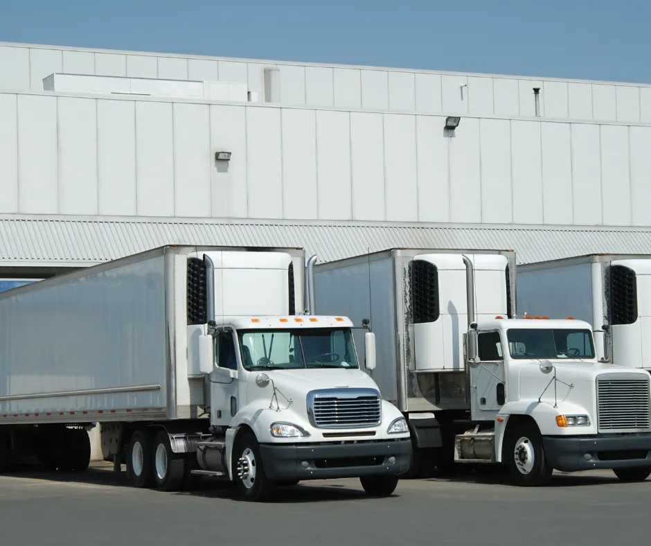 Well-organized logistics hub with multiple trucks being loaded at a docking station, ensuring efficient freight transportation and supply chain management.