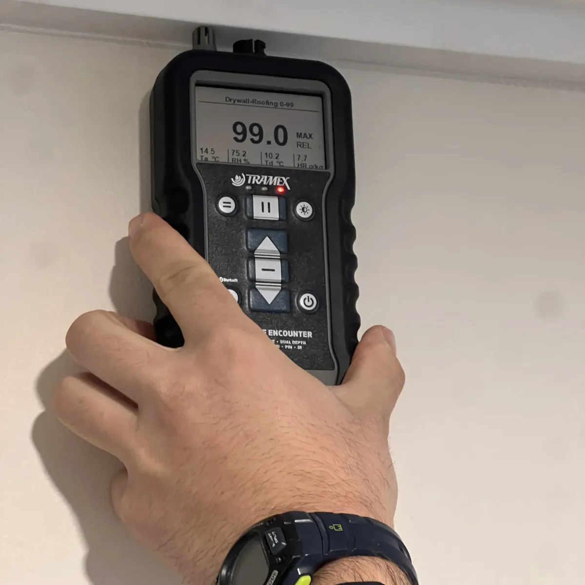 Moisture meter showing high readings during leak detection on interior wall