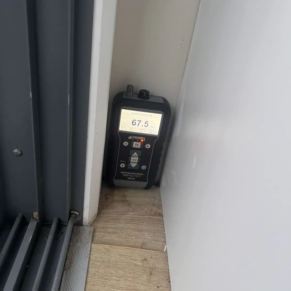 Moisture meter showing high readings during leak detection on interior wall