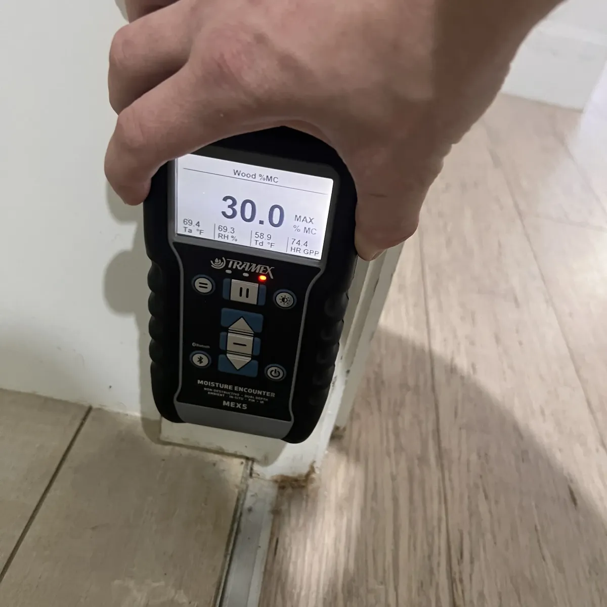 Moisture meter showing high readings during leak detection on interior wall