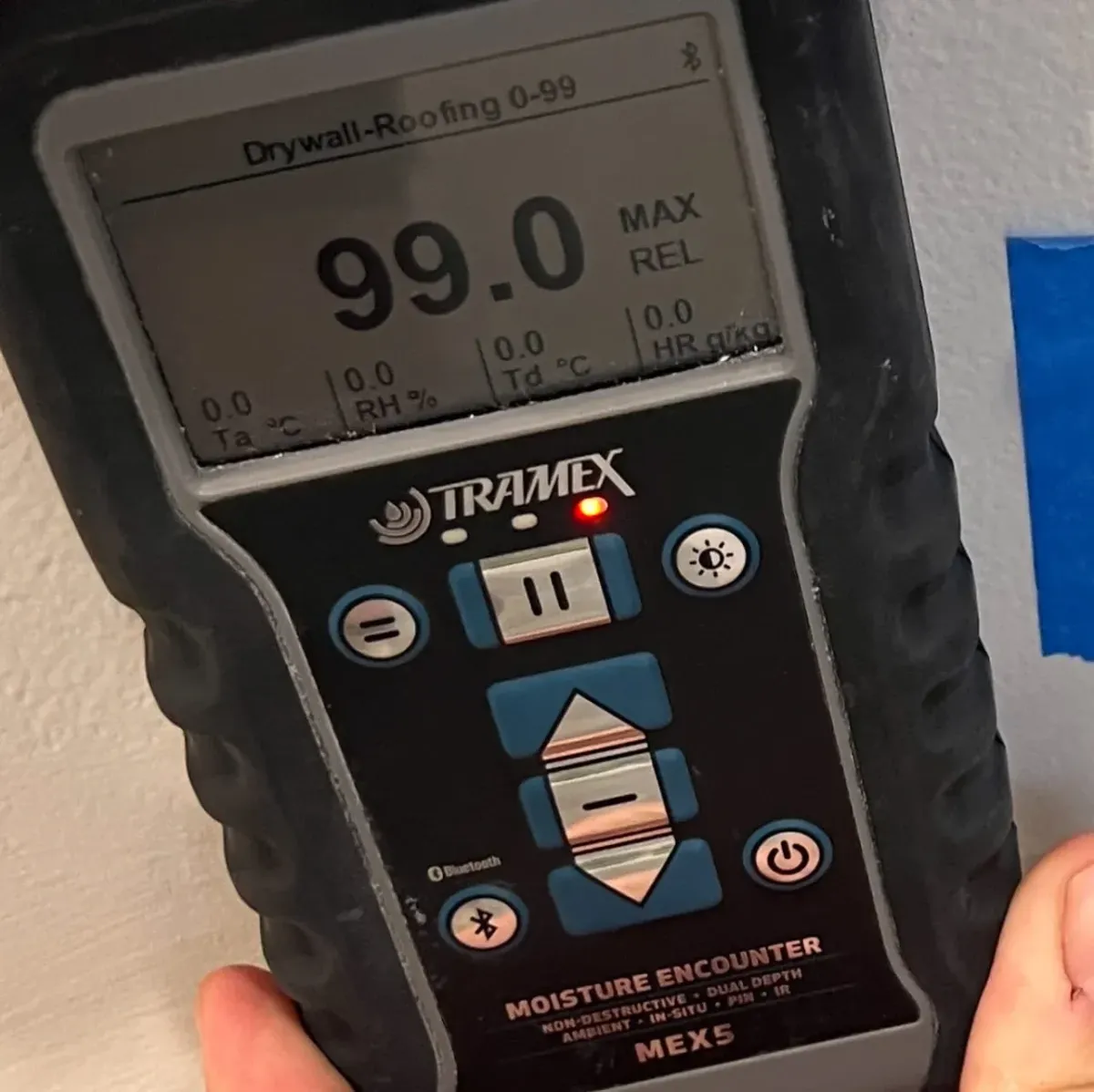 Moisture meter showing high readings during leak detection on interior wall