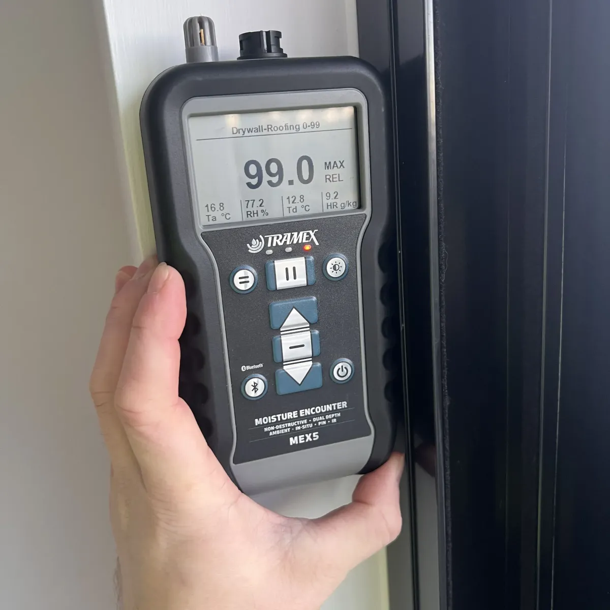 Moisture meter showing high readings during leak detection on interior wall