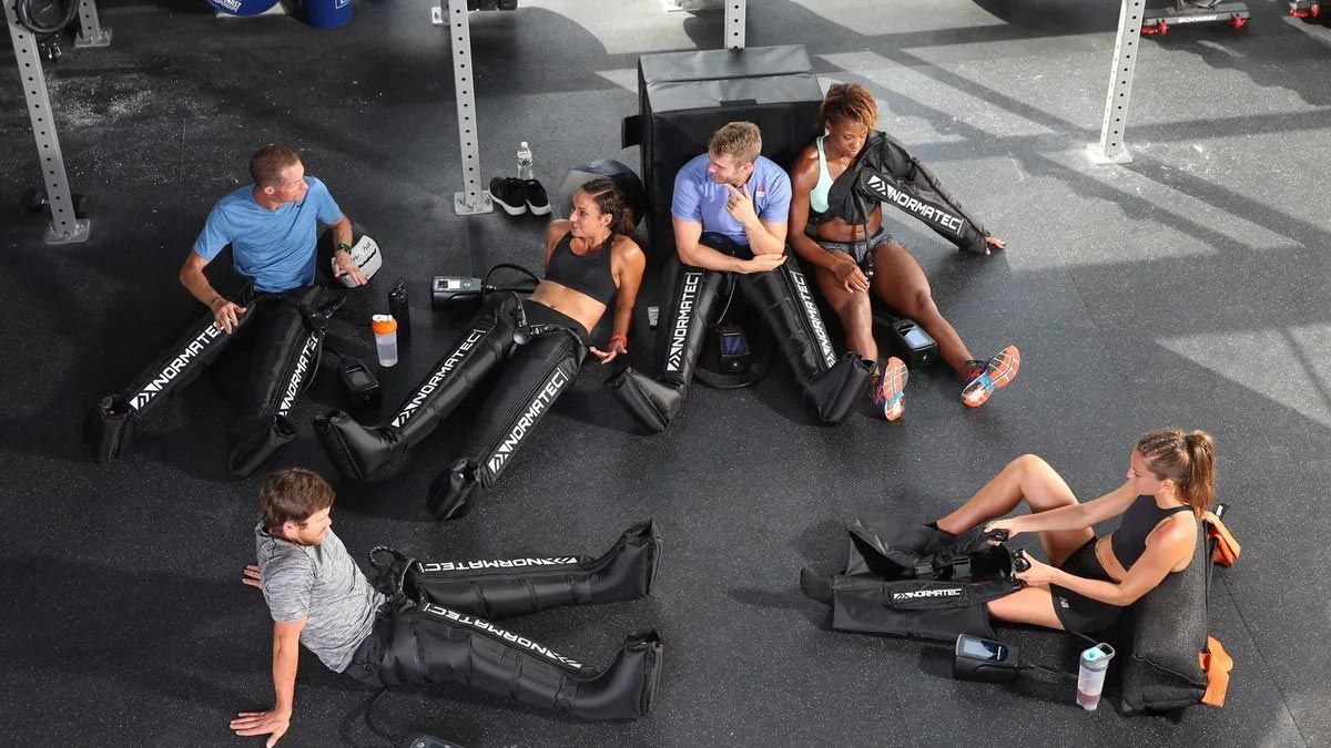 Clients resting with Normatec compression boots after training