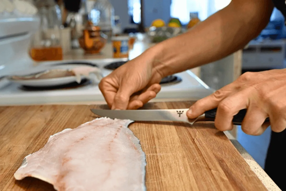 Recreational fisherman using White Tip Spearfishing premium fish filleting knife to slice fresh catch
