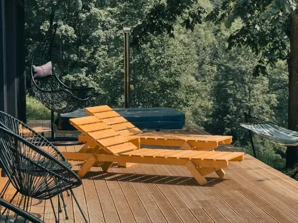 Outdoor deck lounge area with wooden chairs and forest view.