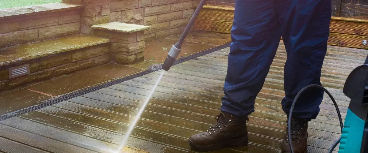 Professional cleaning wooden deck with high-pressure water spray.