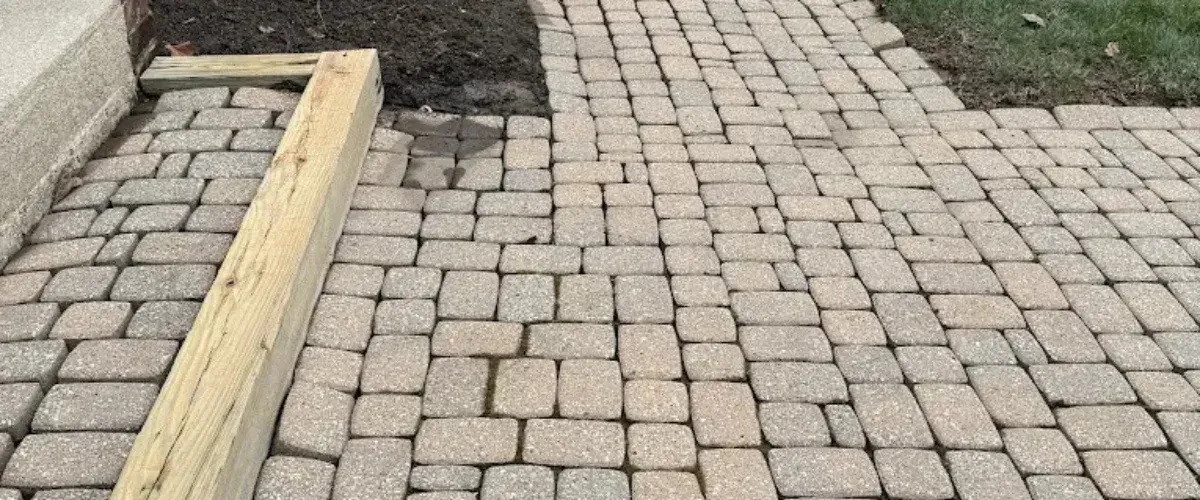 Interlocking concrete paver walkway with uneven stones and grass edges