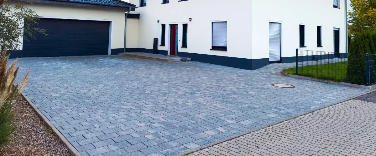 Clean paved driveway in front of modern home with garage and landscaping.