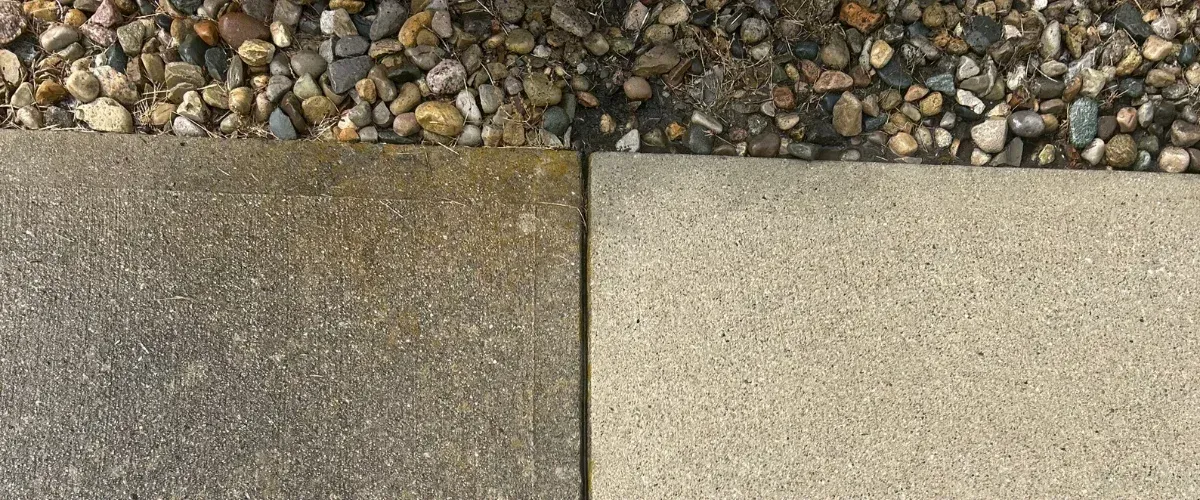 An overhead shot of two concrete sidewalk slabs bordered by a strip of river rocks and small pebbles.
