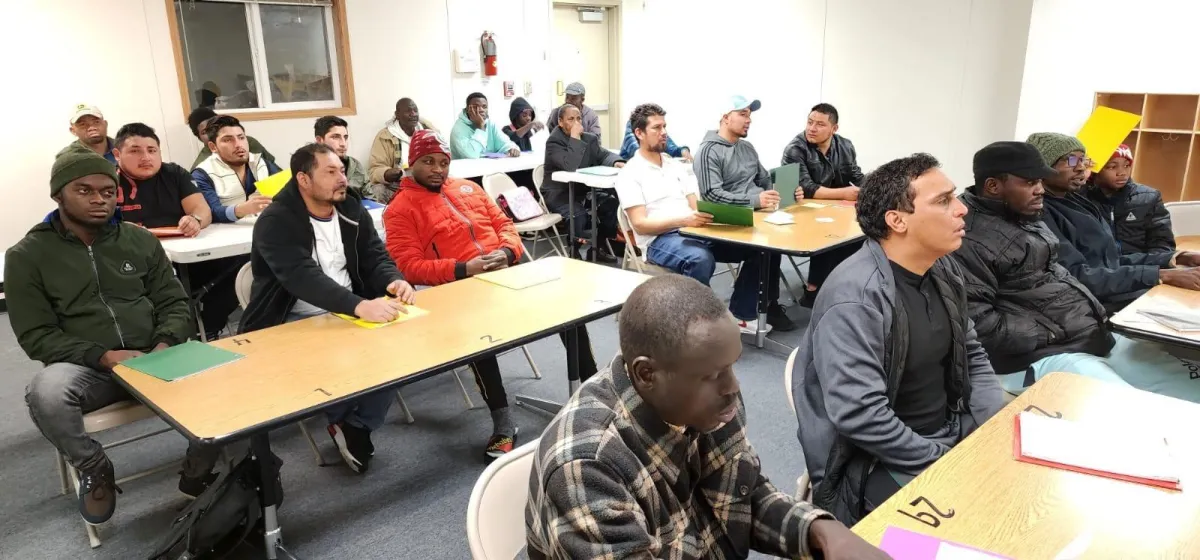 Immigrant students of various nationalities learning English together in a classroom setting