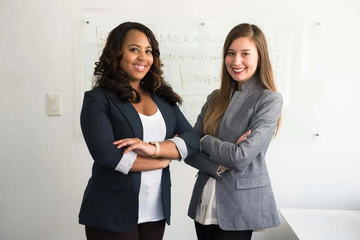 Two smiling business women demonstrate the positive effects of bilingual success coaching