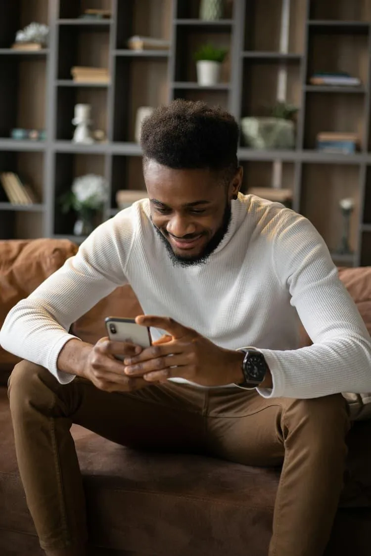 Refugee man smiling as he receive his college placement acceptance on his phone