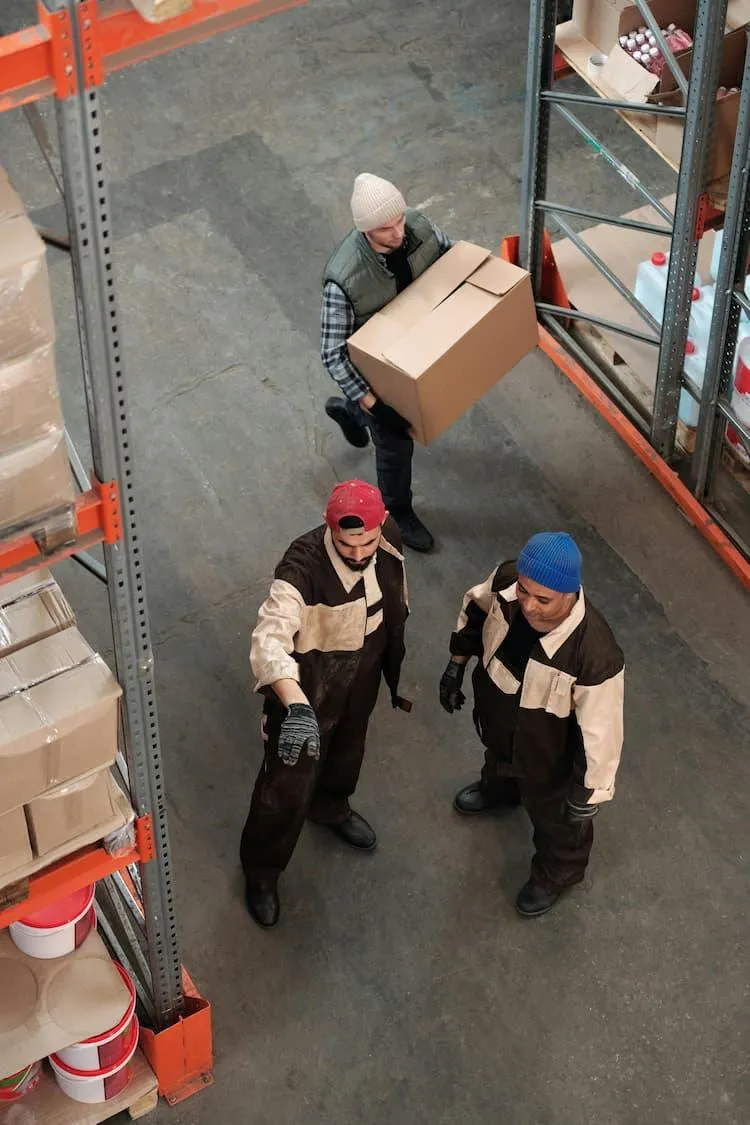 3 Hispanic warehouse workers operate on the warehouse floor following translated OSHA safety standards