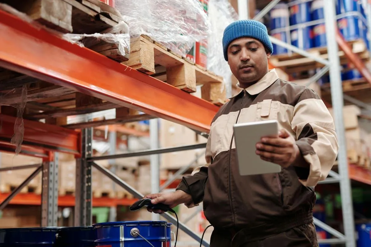 Hispanic warehouse worker examines tablet while pulling orders