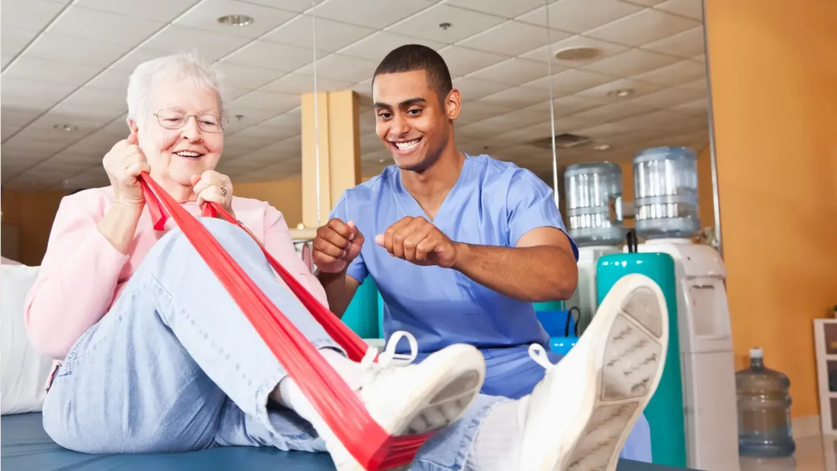 An older woman smiling during a rehabilitation session with a physical therapist, symbolizing recovery and restored health from faulty medical devices.