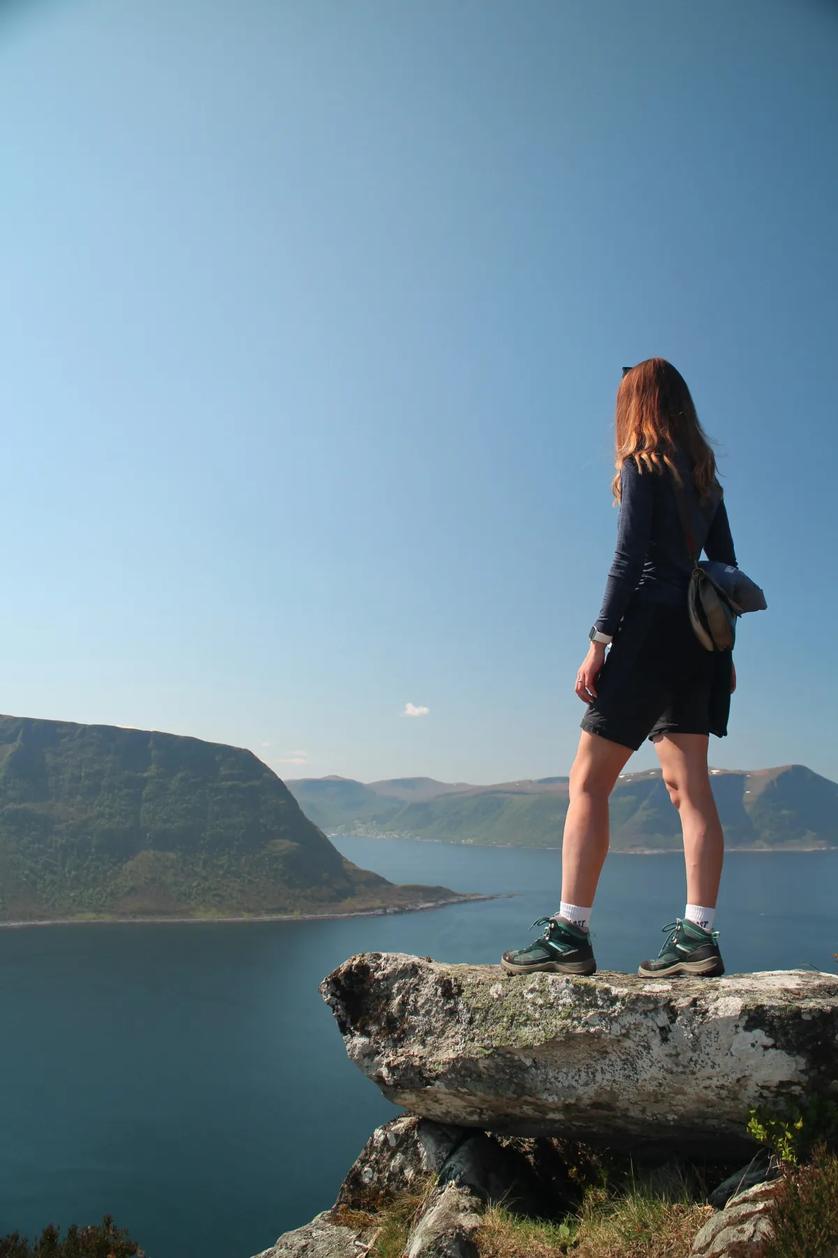 Woman standing atop a scenic hill gazing over a tranquil lake, symbolizing wellness and natural healing near Redmond chiropractic clinic