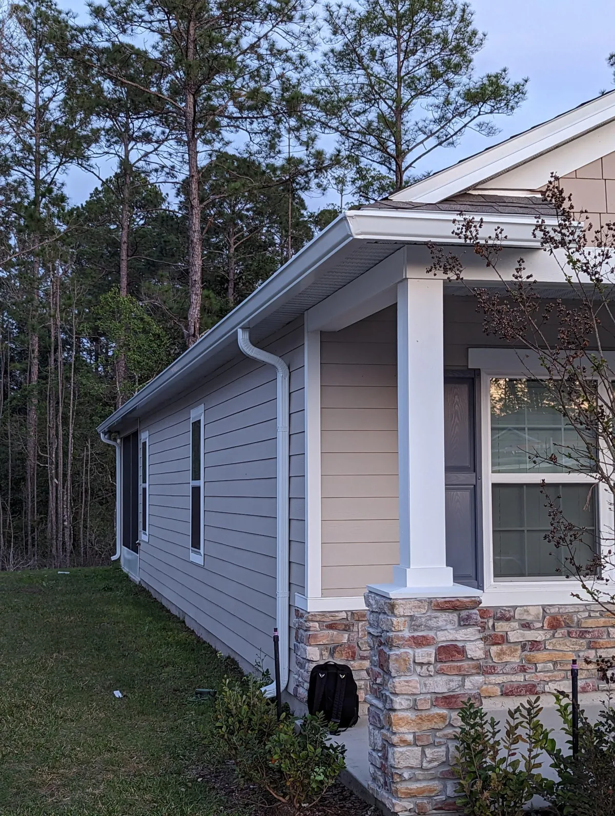 House with newly installed aluminum gutters surrounded by trees, showcasing the professional gutter installation by Clean Gutter Protection.