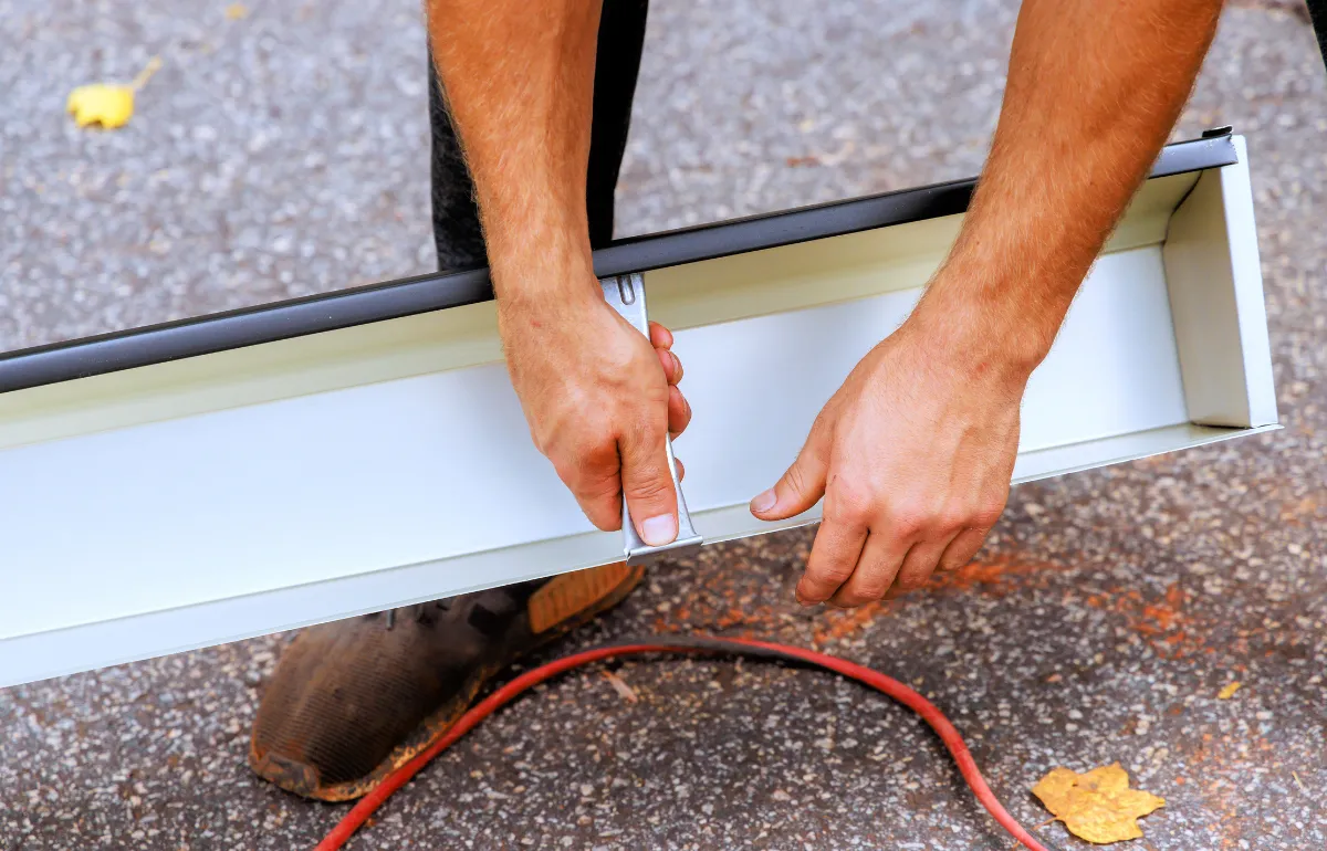 Hands installing a gutter using a mounting system, demonstrating how gutters are securely attached to a home's structure.