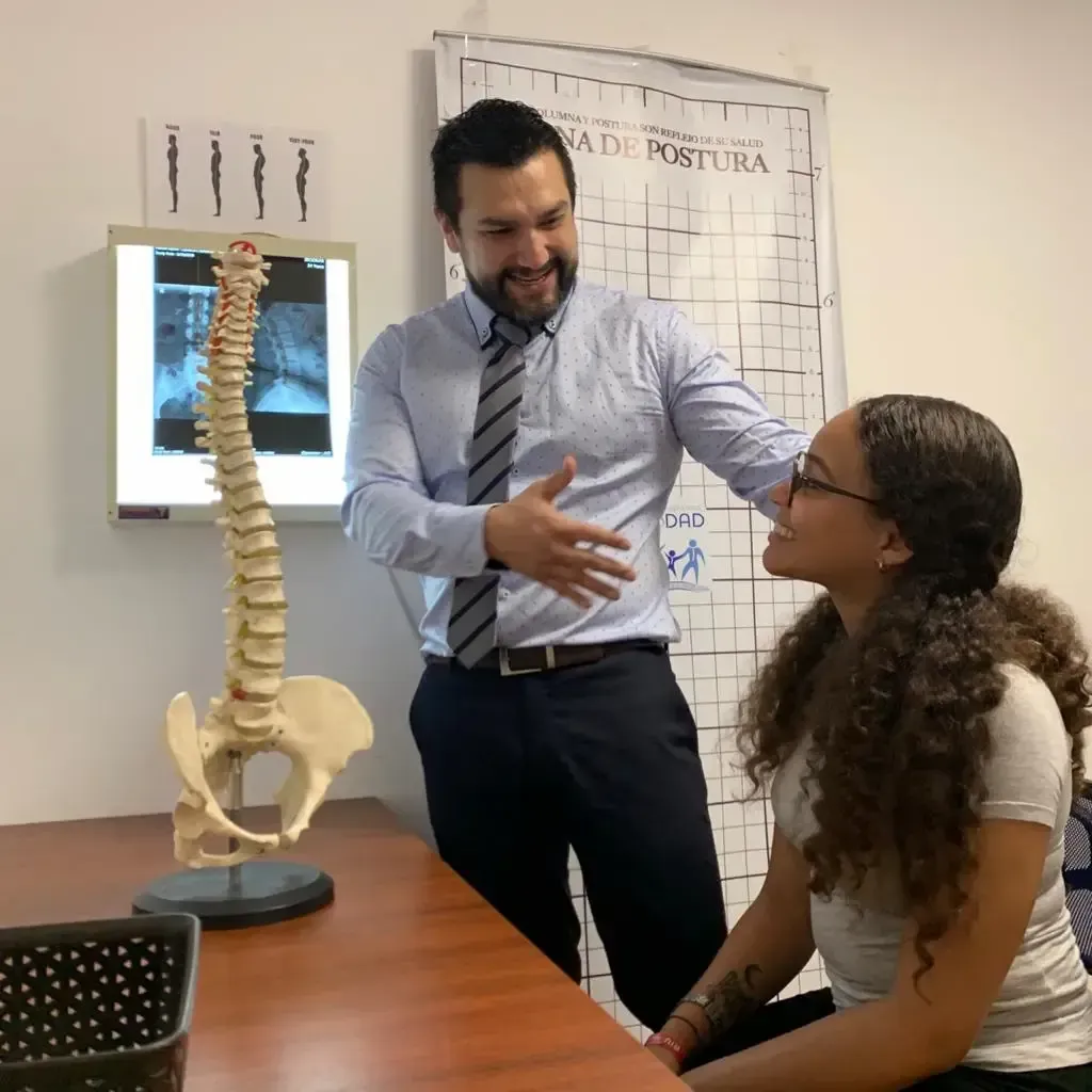 Especialista explicando radiografía de columna a paciente en clínica