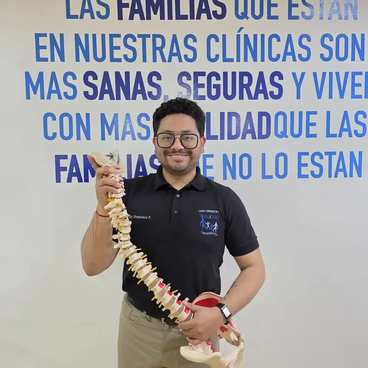 Dr. Pacheco sonriente sosteniendo una columna vertebral en Centro Quiropráctico Vitalidad, nuevo quiropráctico en las sedes de Quito especializado en el cuidado del sistema nervioso y la columna