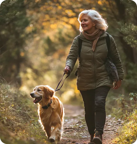 Woman walking golden retriever dog in the forest