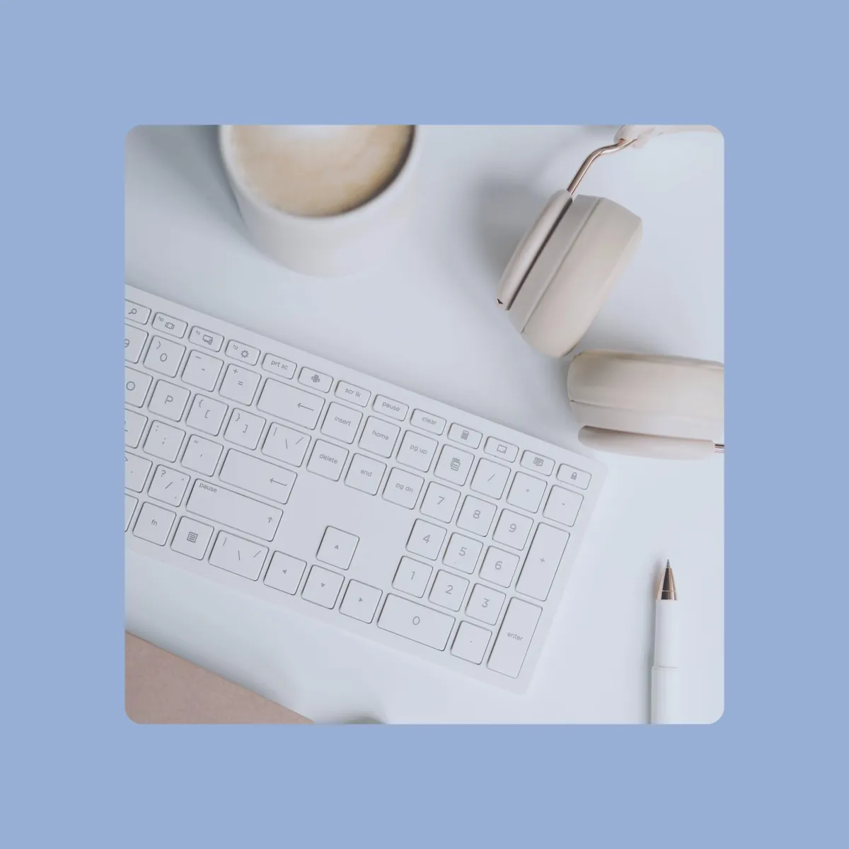 Real estate bloggers desk featuring white keyboard, headphones, and a latte